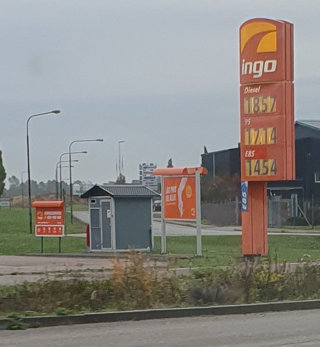 Bensinstation med prisvisarskylt för diesel och bensin under grå himmel.