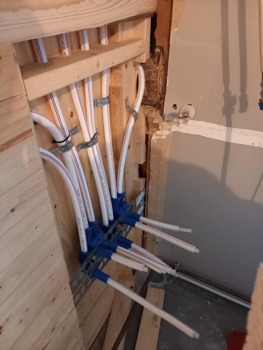 Flexibla rör för kall- och varmvatten dragna genom träreglar i ett renoveringsprojekt.