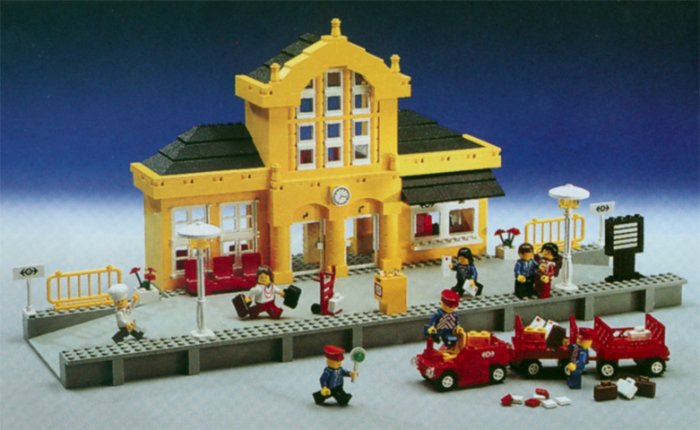 Lego tågstation från tidigt 90-tal med figurer, en bil och tågrelaterade tillbehör.