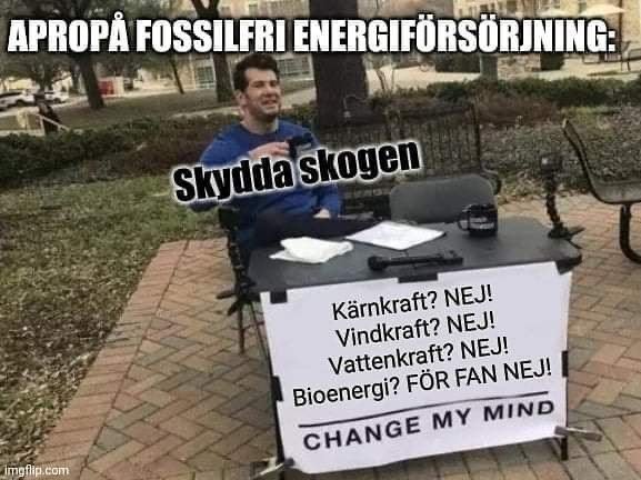 Person vid bord med skylt om energiförsörjning och text "CHANGE MY MIND".