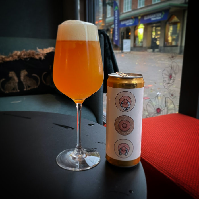 Ett glas öl och en burk öl på ett bord med stadsmiljö i bakgrunden.