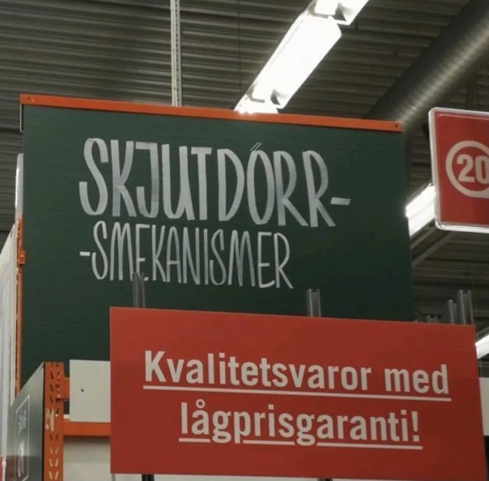 Skylt med texten "SKJUTDÖRR-MEKNISMER" över en röd skylt som säger "Kvalitetsvaror med lågprisgaranti!".