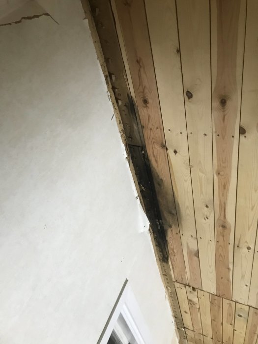 Renoverat kök med rivet tak visar en skada vid träbjälkarna, möjlig vattenskada ovanför.