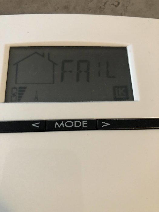 Digital display på en apparat som visar ordet "FAIL" med en hus-ikon och batterisymbol.