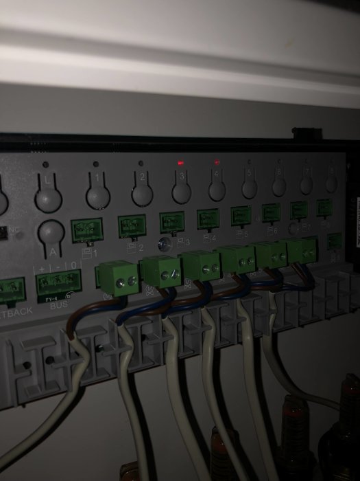 Elektrisk kopplingspanel med termostater där två dioder lyser rött och kablar anslutna.