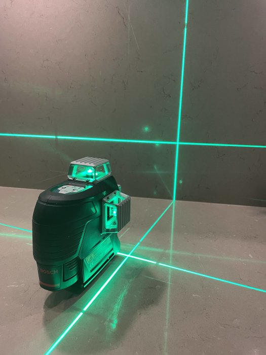 Ny Bosch laser, GLL3-80 CG, projicerar gröna laserlinjer på en grå yta.