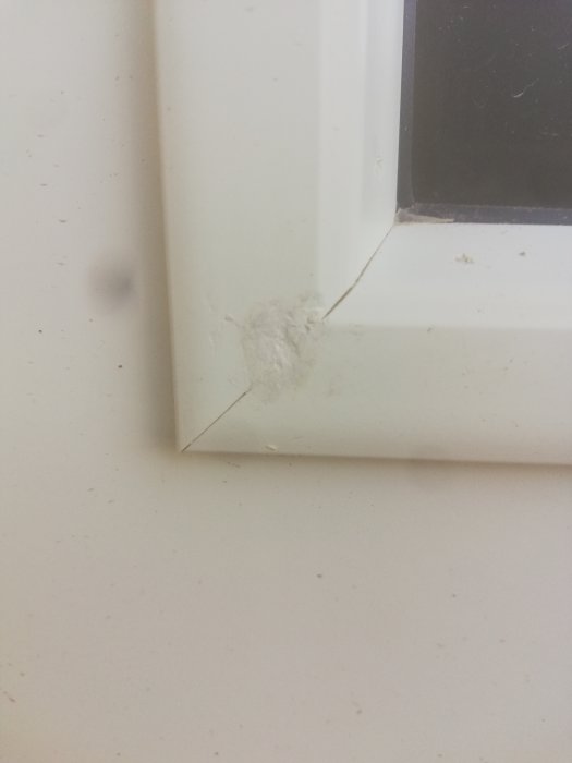 Spackel eller reparatorfärg på en vit glaslist till en dörr, som visar tecken på reparation.