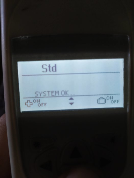 Handhållen fjärrkontrollens display visar "Std", "SYSTEM OK", samt ikoner för påslagning och avstängning.