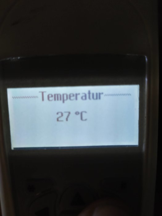 Fjärrkontrollens display visar en inställd temperatur på 27 grader Celsius.