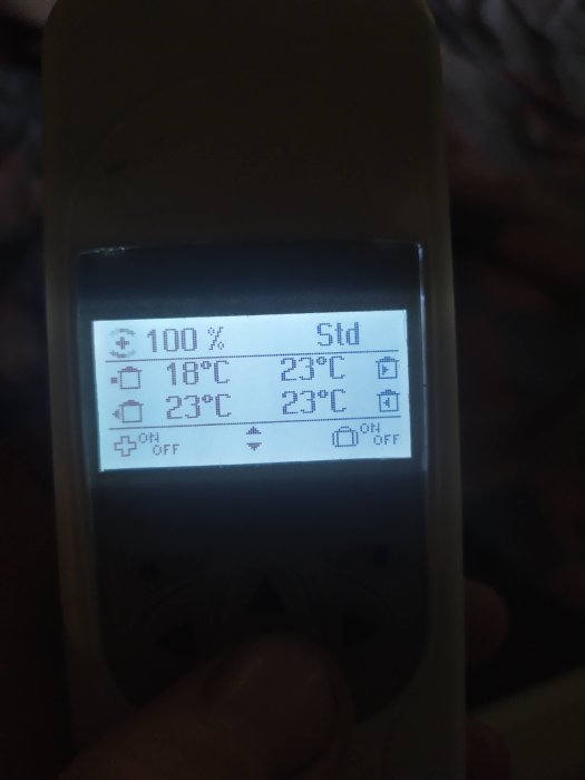 Termostat visar aktuell och önskad temperatur på display med ikoner för batteri och inställningar.