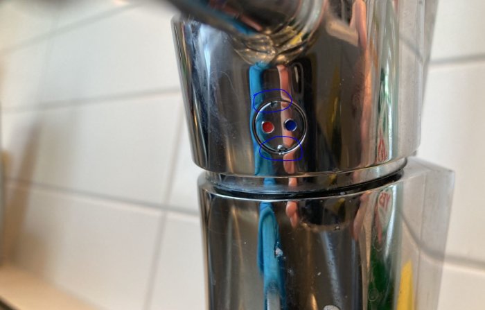 Närbild på kromad vattenkran med cirklade märken som indikerar skador från verktyg användning.