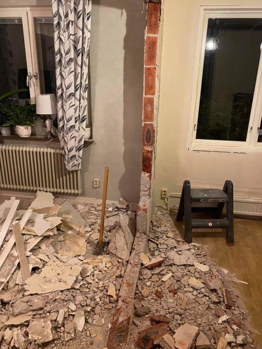 Renoveringsarbete visar en delvis rivet tegelvägg och träreglar med byggbråte på golvet.