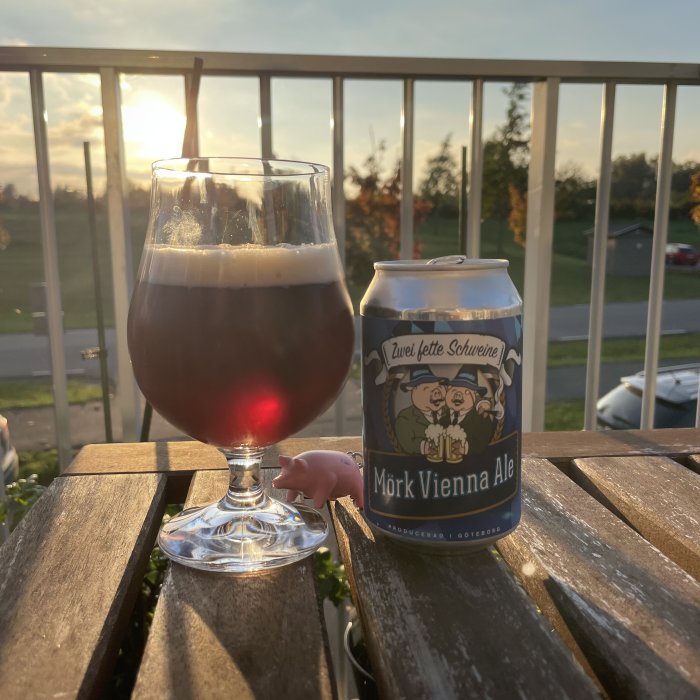 Ett glas mörk Vienna Ale på ett bord vid solnedgång med burken bredvid.