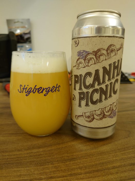 En burk Burley Oak Brewing Co. öl bredvid ett glas med öl på ett brunt bord.