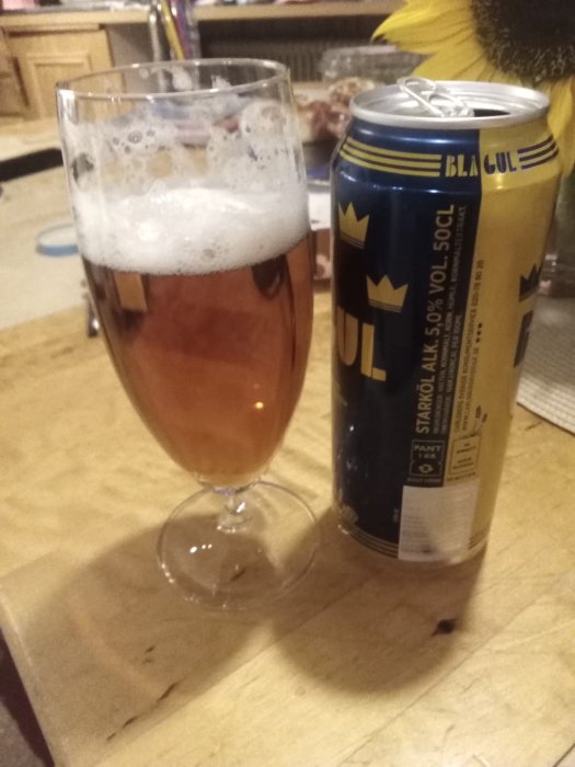 Ett glas öl och en ölburk på ett bord.