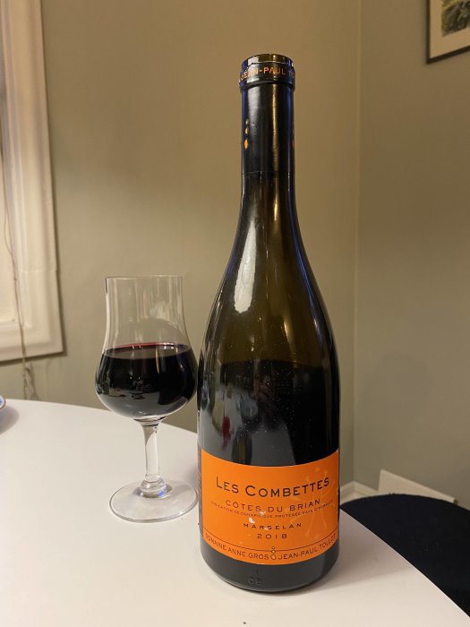 Flaska och glas med rödvin, etikett visar "Les Combettes Marselan 2018" från Languedoc.