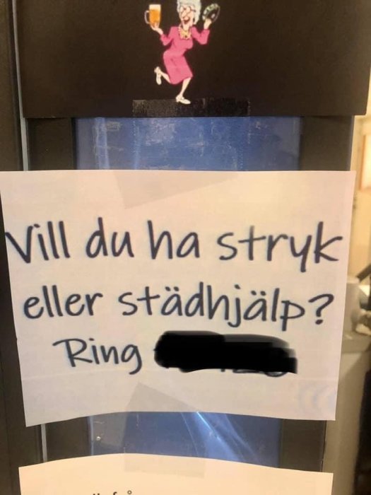 Lapp med text "Vill du ha stryk eller städhjälp? Ring" och tecknad figur som håller i ett glas och en stekpanna.