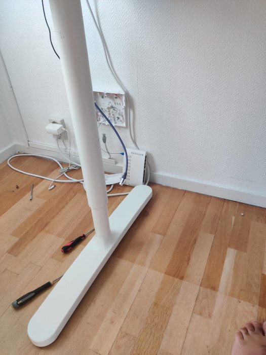 Skadad fiberkabel och öppen fiberkonverter på golvet vid en vägg.