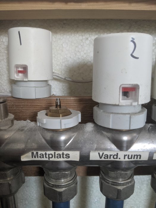 Värmesystemets termostatventiler med etiketter "Matplats" och "Vard. rum", visar röda indikatorer i olika lägen.