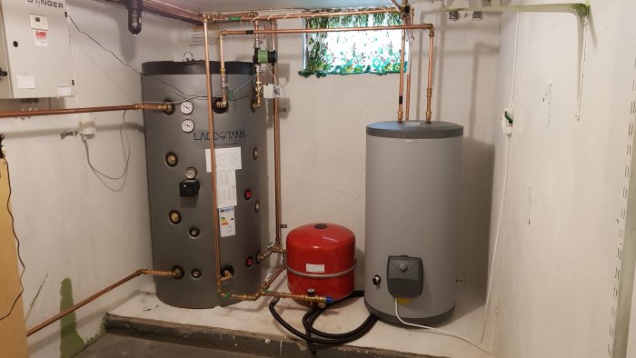 Installation av värmesystem med kopparledningar, expansionskärl och varmvattenberedare i ett pannrum.