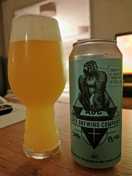 Ett glas med Apex Maelstrom DIPA bredvid dess burk på ett bord.