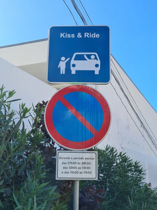 Skyltar för 'Kiss & Ride'-zonen och parkeringsförbud med tidsbegränsningar vid skola.
