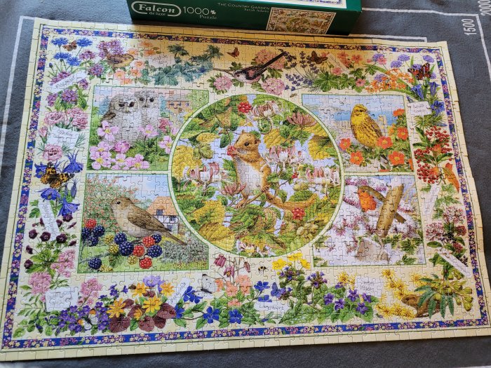 Komplett pussel med motiv av trädgård och vilda djur som fåglar och igelkottar, lagt på en matta.