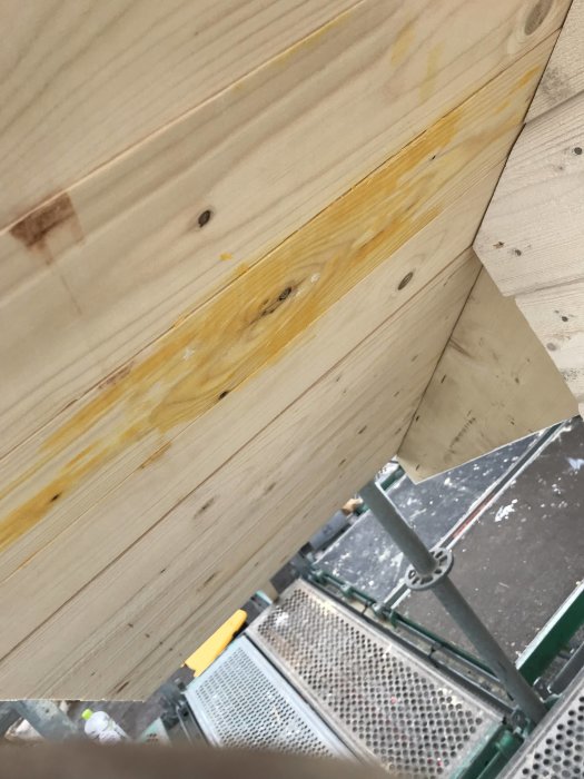 Råspont med gulbrunt klet vid takutsprånget, synbara fuktskador, i bakgrunden en stegplattform.
