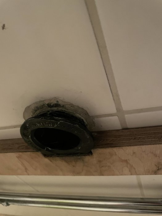 En svart 50/40 nippel som sitter i en vägg med vita kakelplattor, inte helt insatt.