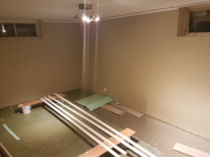 Oinrett källarrum i renoveringsfas med laminatgolv delvis lagt, limrester och byggmaterial.