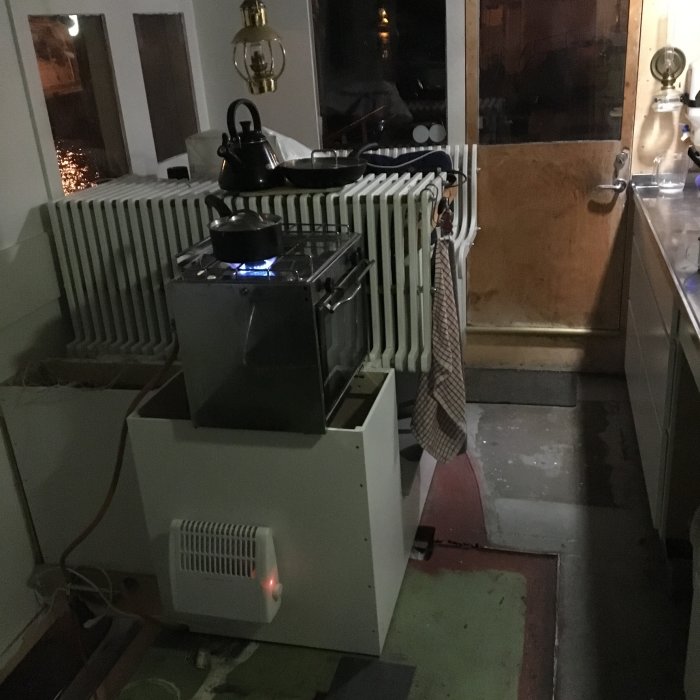 Provvisoriskt kök med temporär värmekälla och vattenkokare ovanpå vit skåpbas.