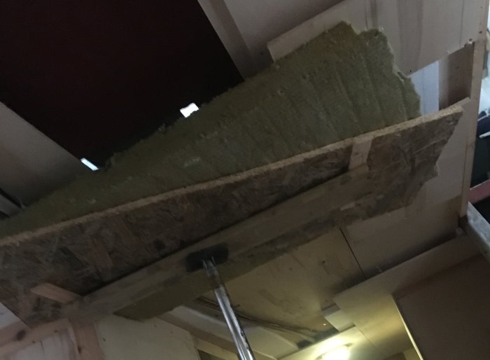 Insida av ett byggprojekt med en uppklämd markskiva i takkonstruktionen.
