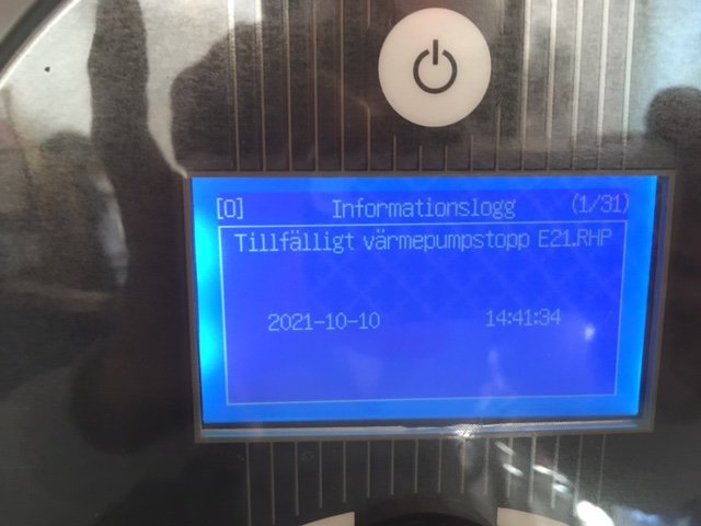 Display på värmepump som visar felmeddelande "Tillfälligt värmepumpsstopp E21.RHP" med datum och tid.