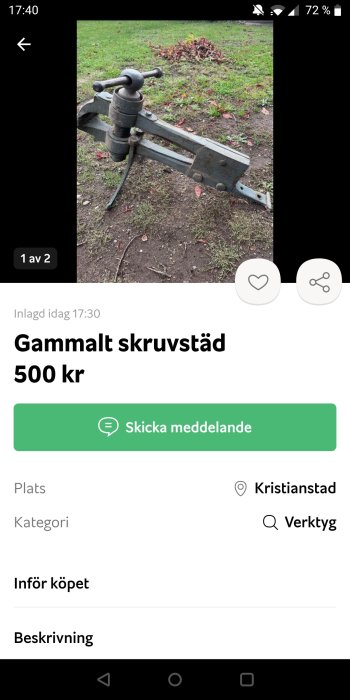 Gammalt skruvstäd av metall på gräs.