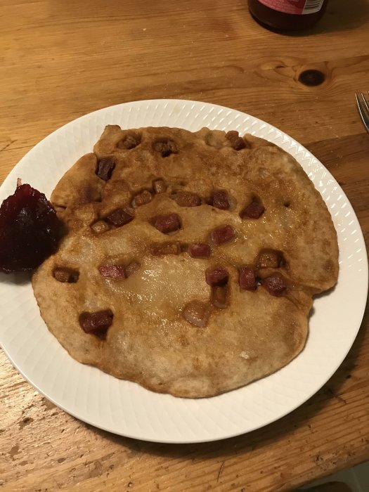 Kolbulle med bitar av amerikafläsk på en tallrik bredvid en klick lingonsylt.