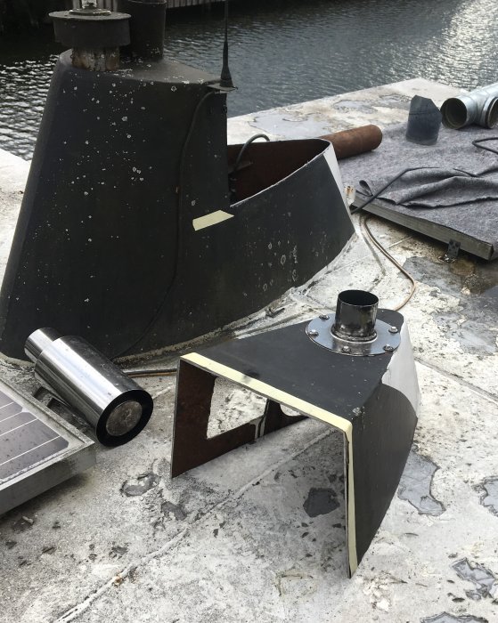 Byggnadsmaterial och verktyg på ett tak, inklusive metallrör och kaminsektioner under arbete.