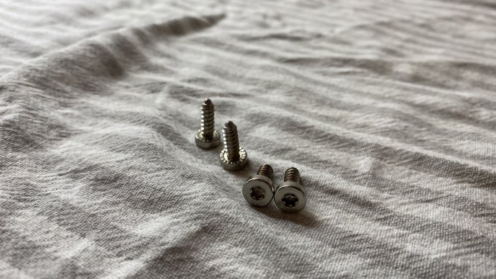 Fyra T-20 skruvar på en grå tygyta som används i ett byggprojekt för att reparera en köksspis.