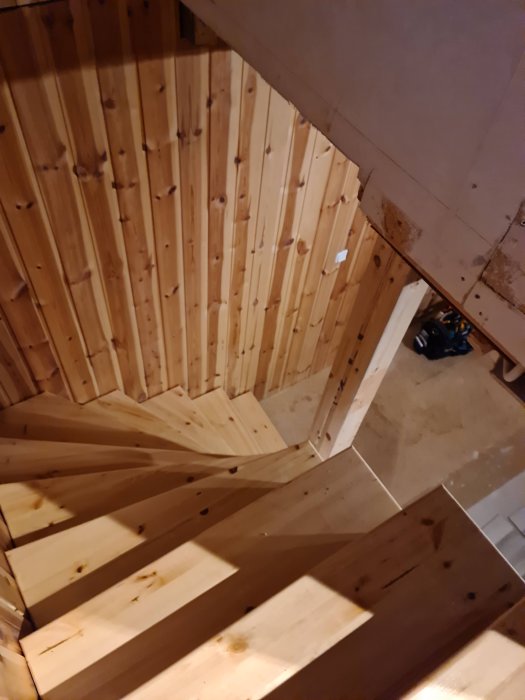 Nykonstruerad trätrappa inomhus utan sättsteg, vy uppifrån i ett orenoverat utrymme.