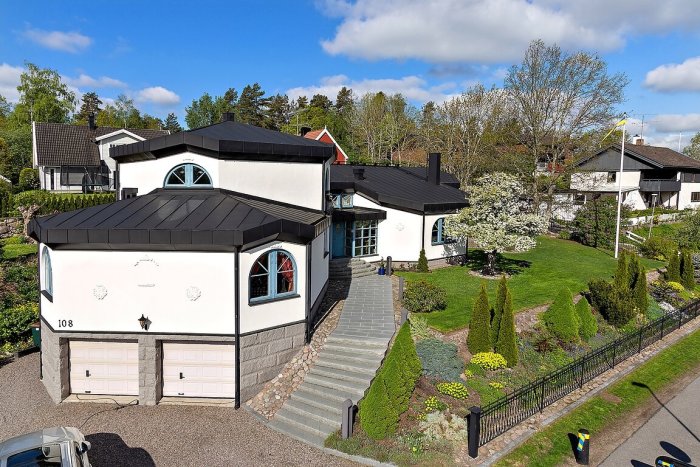 Vit villa med svart tak och runda fönster som liknar Barbapappas hus.