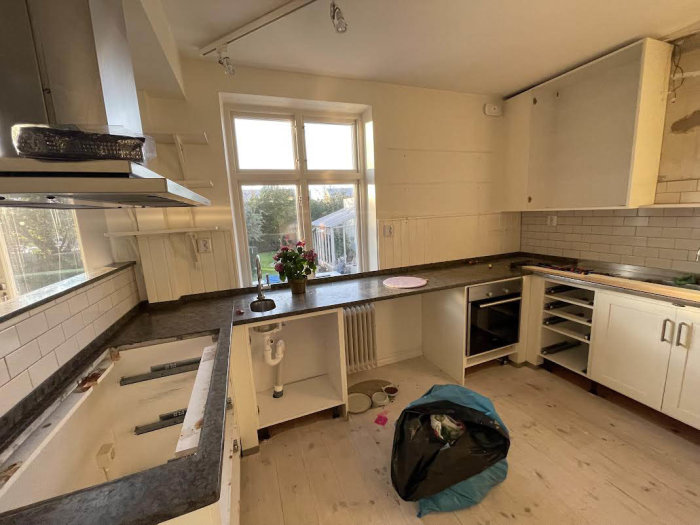 Kök under renovering med borttagna skåpluckor, öppna lådor och kvarstående diskho.