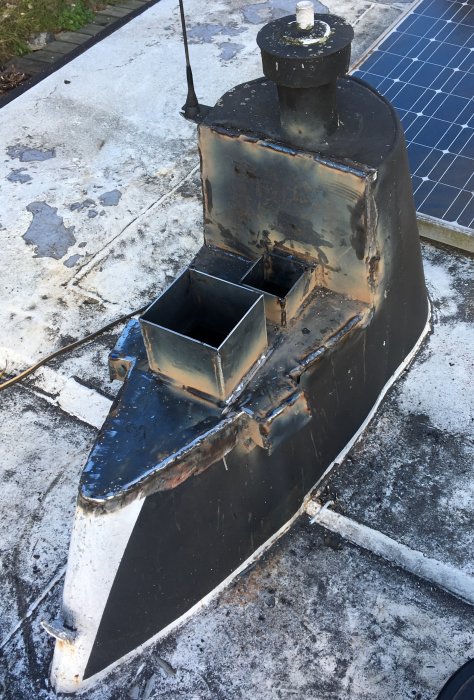 Svetsad takgenomföring för skorstenar på ett båttak med solpanel i bakgrunden.