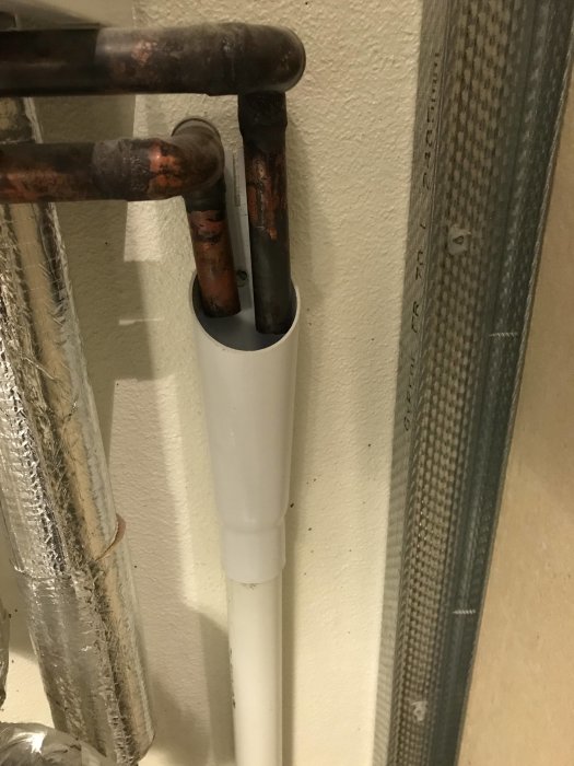 Avloppsrör med kopparledning i ett hushåll, misstänkt källa till avloppslukt.