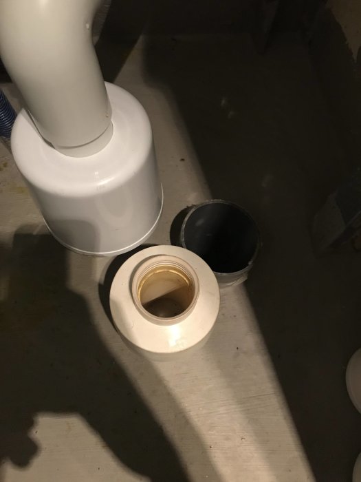Avloppsrör och öppning i betonggolv som luktar avlopp i ett radhus badrum.