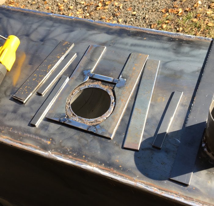 Metallplåt med utskuret hål och svetsade detaljer för tillverkning av kamin.
