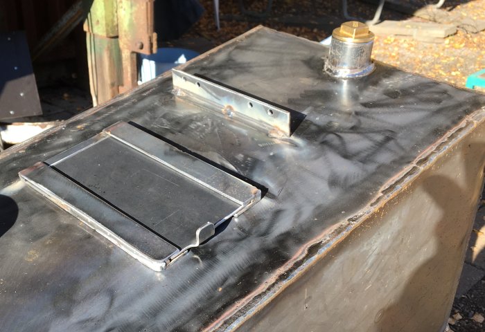 Svetsade delar på en kamin med en stängd lucka och ett spjäll för tilluften synlig överst på bild.