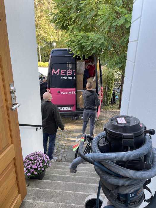 Leverans av kökselement till ett hus, arbetare bär in paket från en parkerad leveransbil.
