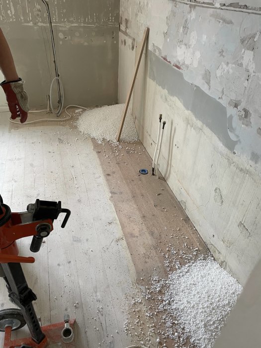 Renoveringsarbete med cellplastsisolering på golv och håltagning i vägg för installation.