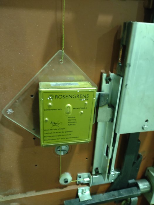 Rosenarens gammalt kombinationslås av modell CNAB-6 på en säkerhetsdörr med varningstext om att inte smörja låset.