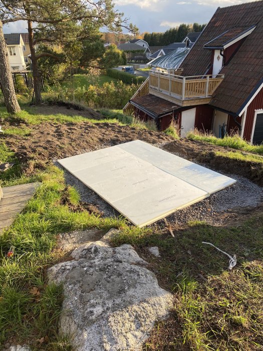 Ett spabadlock i trädgården som ligger på marken bredvid en grävd plats för installation.