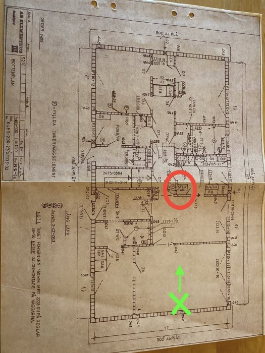 Byggplan över en våning med markerat kryss och riktning visad med en grön pil.